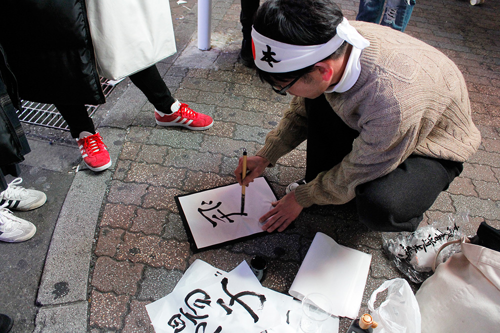 道端で無料で書道に応じる人