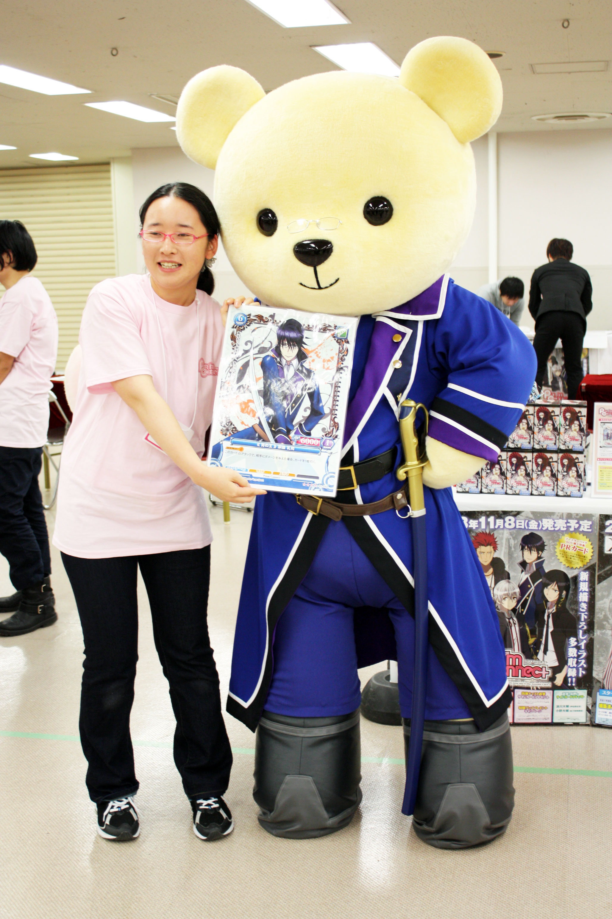 「プリズムコネクト」ブースに現れたのは、スタッフさんが手に持つ宗像さんカードとお揃いの「青のクラン・セプター4」の制服を身に纏った大きいくまメイトさん